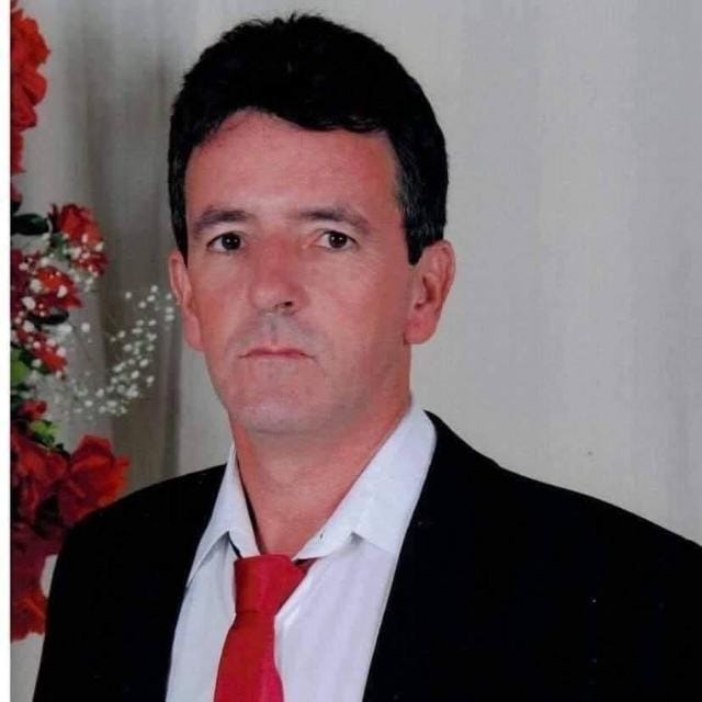 Dr. Zezinho de terno preto, camisa branca e gravata vermelha